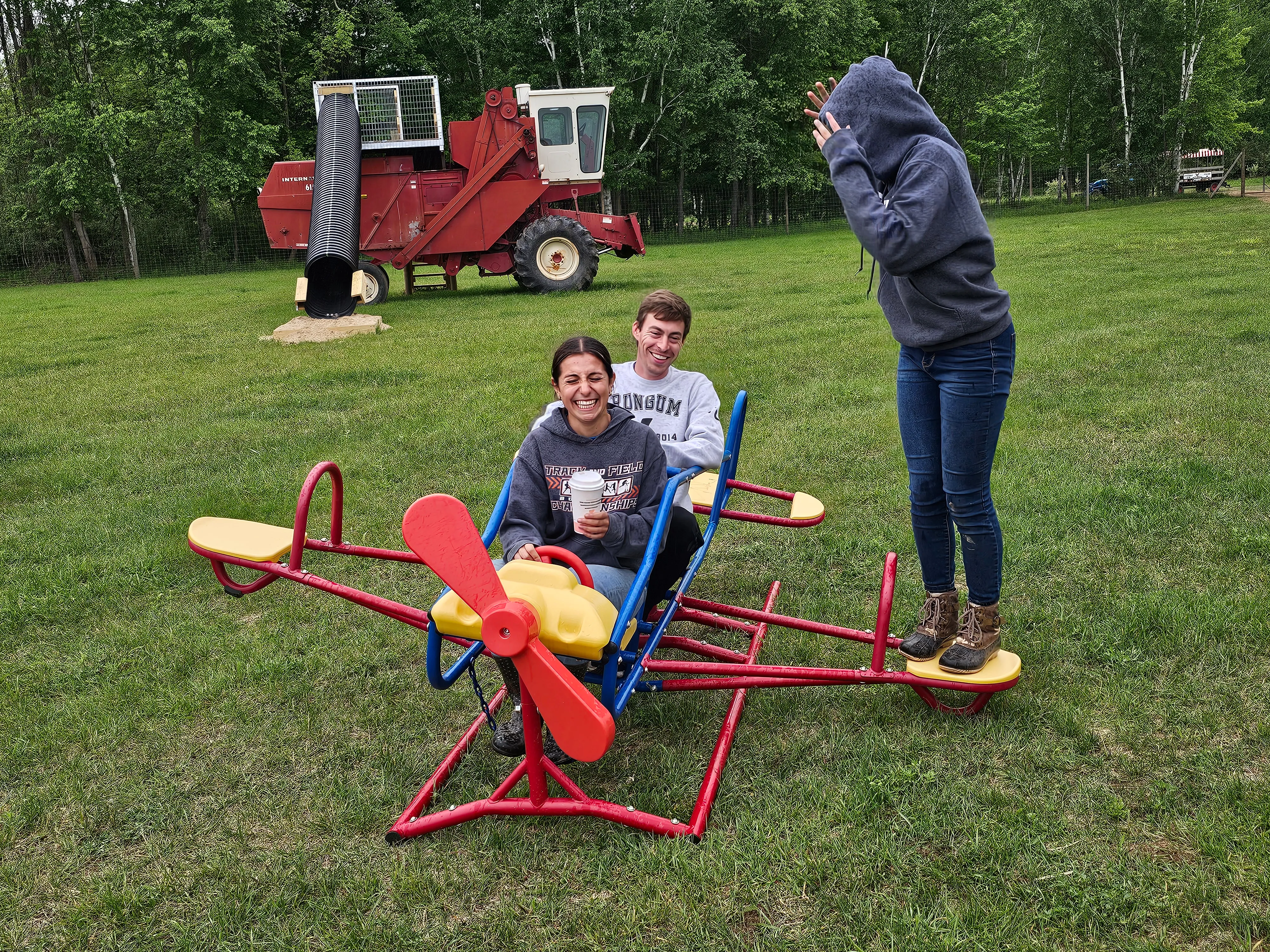 Kids and parents riding a red airplane-shaped teeter-totter together