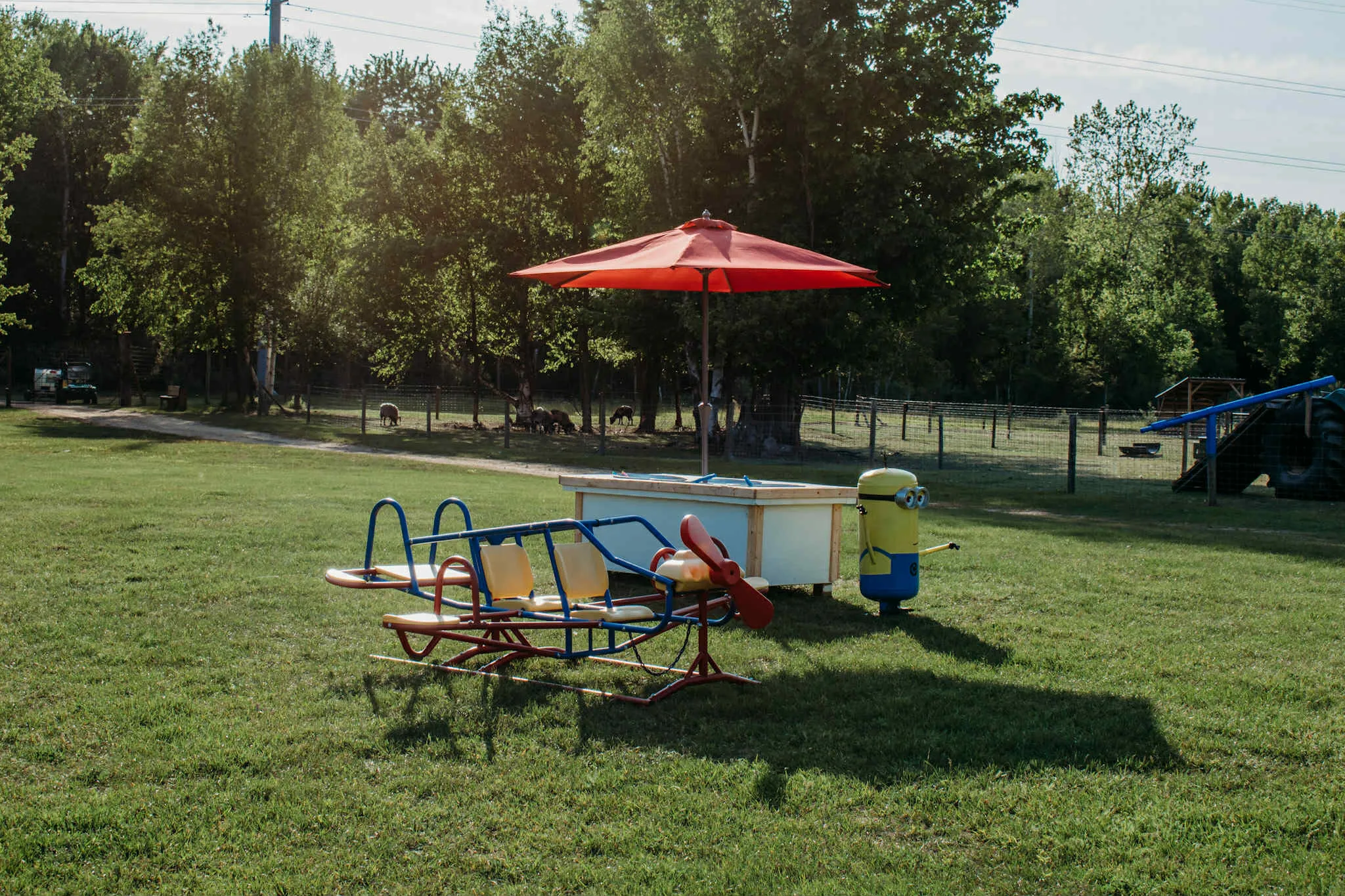 The airplane teeter-totter and shaded picnic umbrella area in the playground