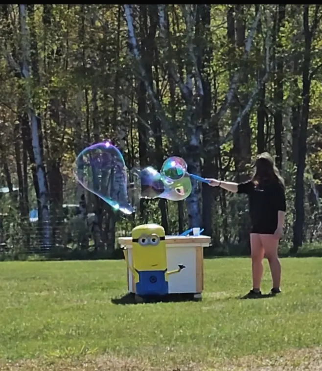 A visitor blowing giant bubbles next to a minion mascot at the ranch